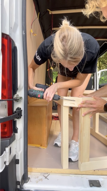 Saskia drilling the bed frame inside the van