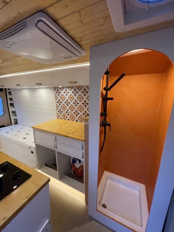 The arched, burnt-orange indoor shower next to the kitchen